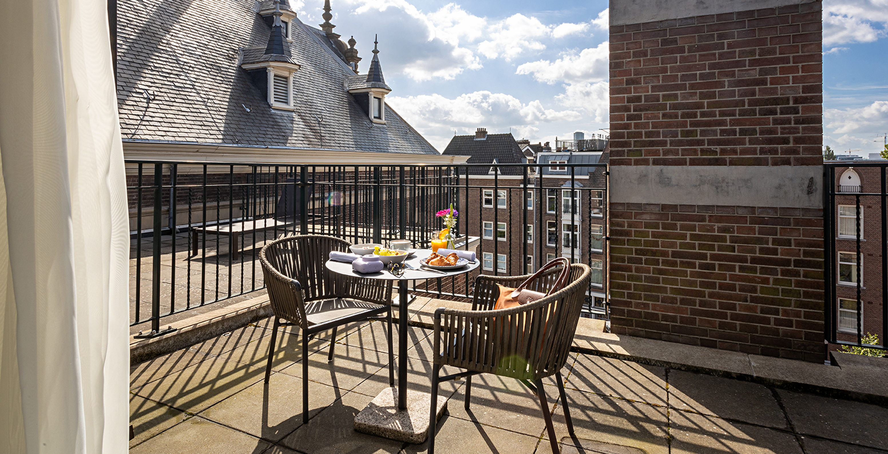 De Superieure met Terras kamer van Pestana Amsterdam Riverside heeft een balkon met een tafel en twee stoelen
