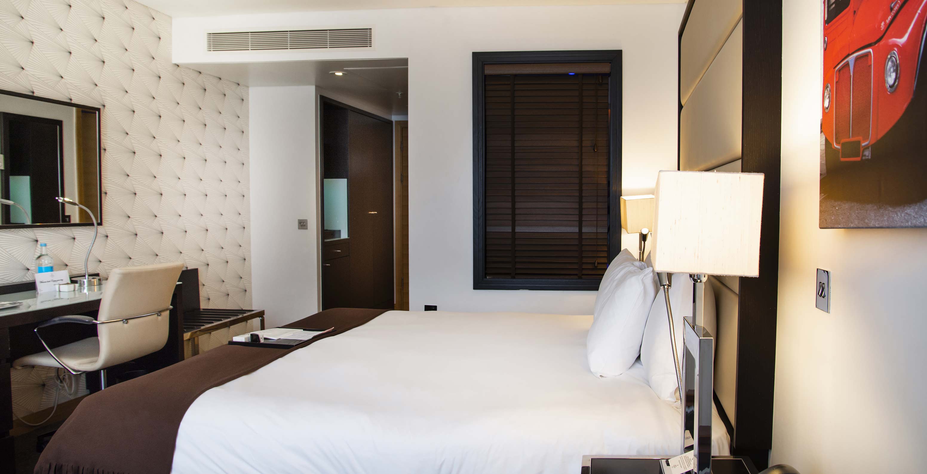 De Premium King van Pestana Chelsea Bridge heeft een tweepersoonsbed met witte lakens, bureau met stoel en spiegel