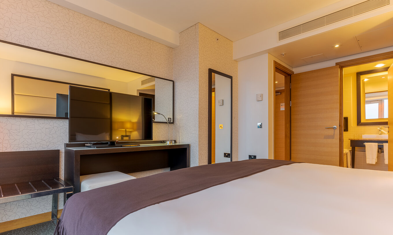 De Executive One Bedroom Suite van Pestana Chelsea Bridge heeft bed, tv, twee spiegels en een badkamer