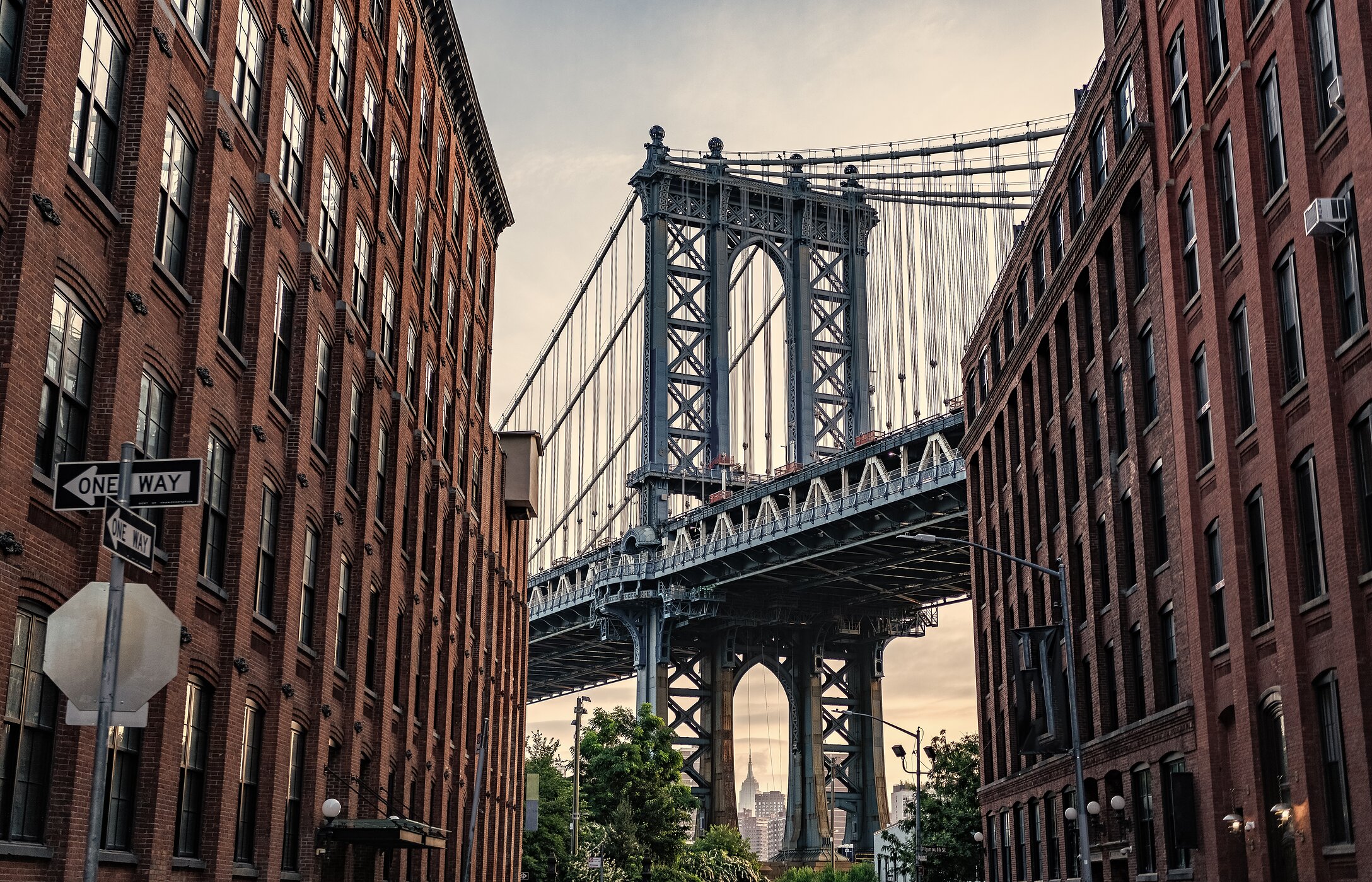 Uitzicht op de iconische Brooklyn Bridge, tussen gebouwen, die Manhattan met Brooklyn in New York City verbindt