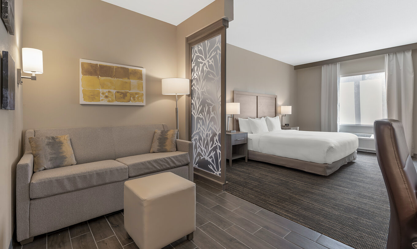 De ADA King Suite Van Pestana Orlando Suites Lake Buena Vista Heeft Een Tweepersoonsbed Een Nachtkastje Sofa En Lamp