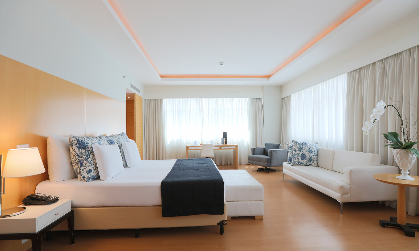 A King Suite Executiva do Pestana Curitiba é bastante espaçosa e luminosa, com cama de casal king size, sofá e uma secretária