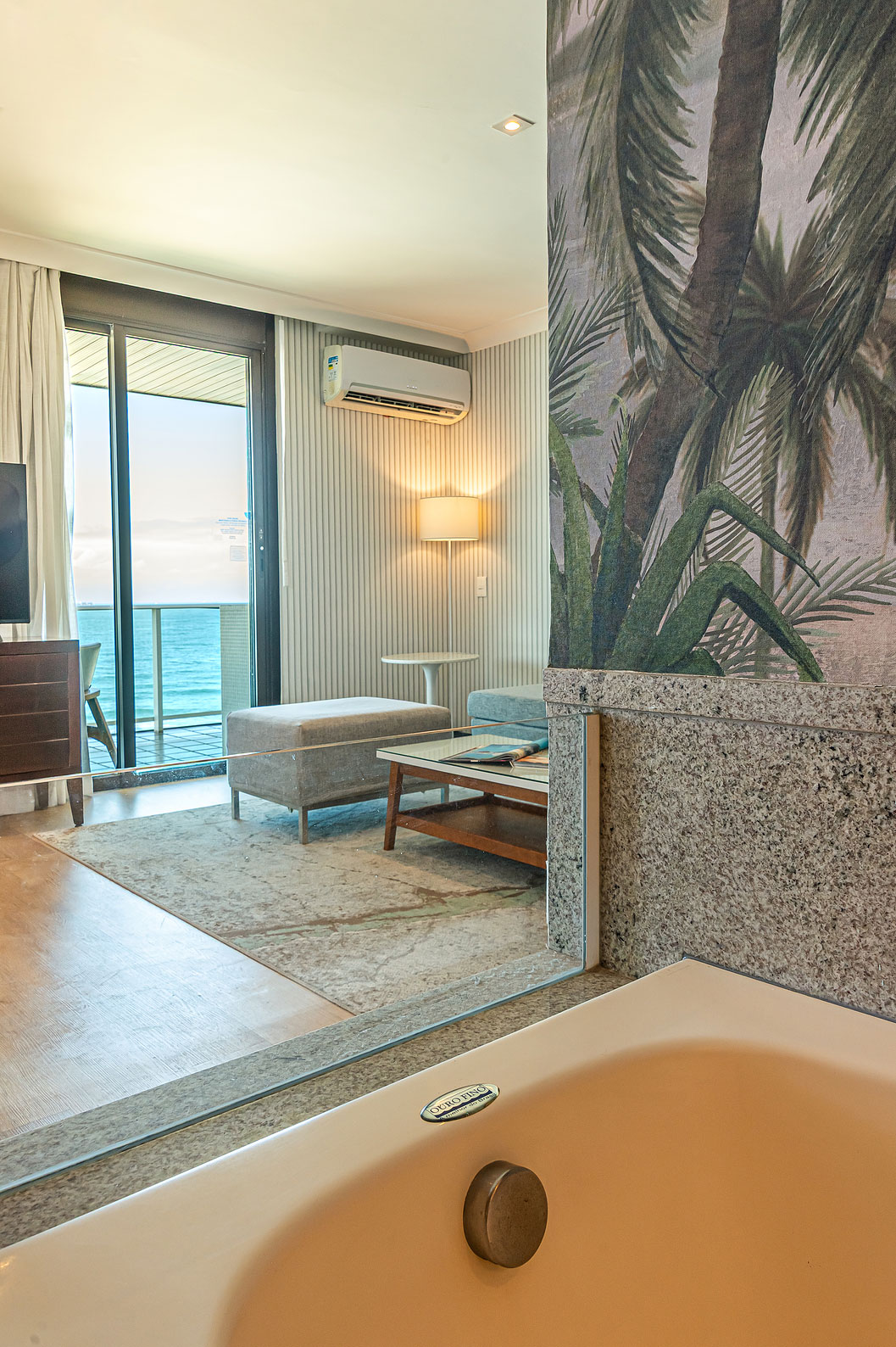 A Suite Oceânica do Pestana Rio Atlântica tem uma sala com sofá, televisão e vista para o mar através da varanda