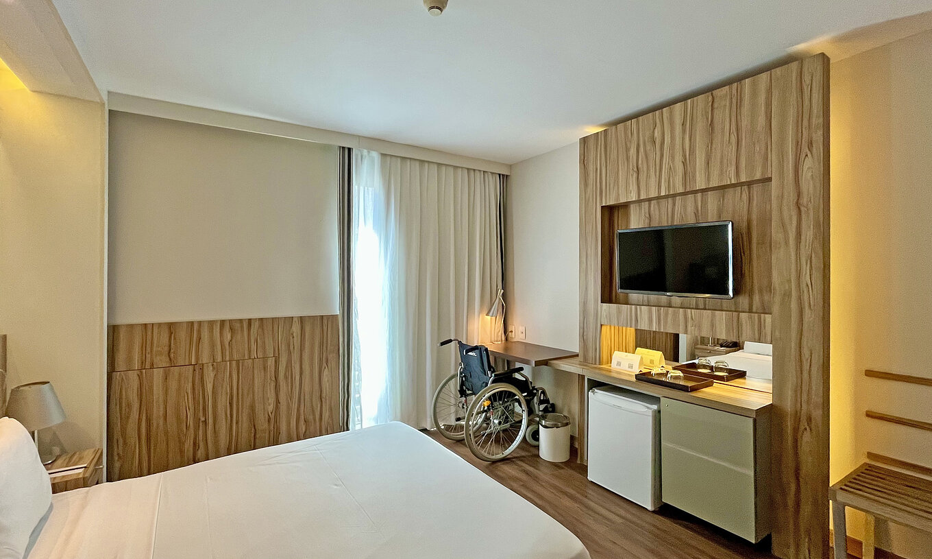 O Quarto Adaptado do Pestana Rio Atlântica tem uma cama de casal e uma secretária com uma cadeira de rodas