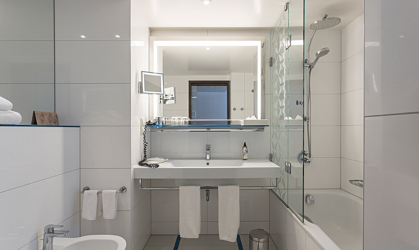 O Family Deluxe do Pestana Berlin Tiergarten tem uma casa de banho com banheira e duche, lavatório e espelho