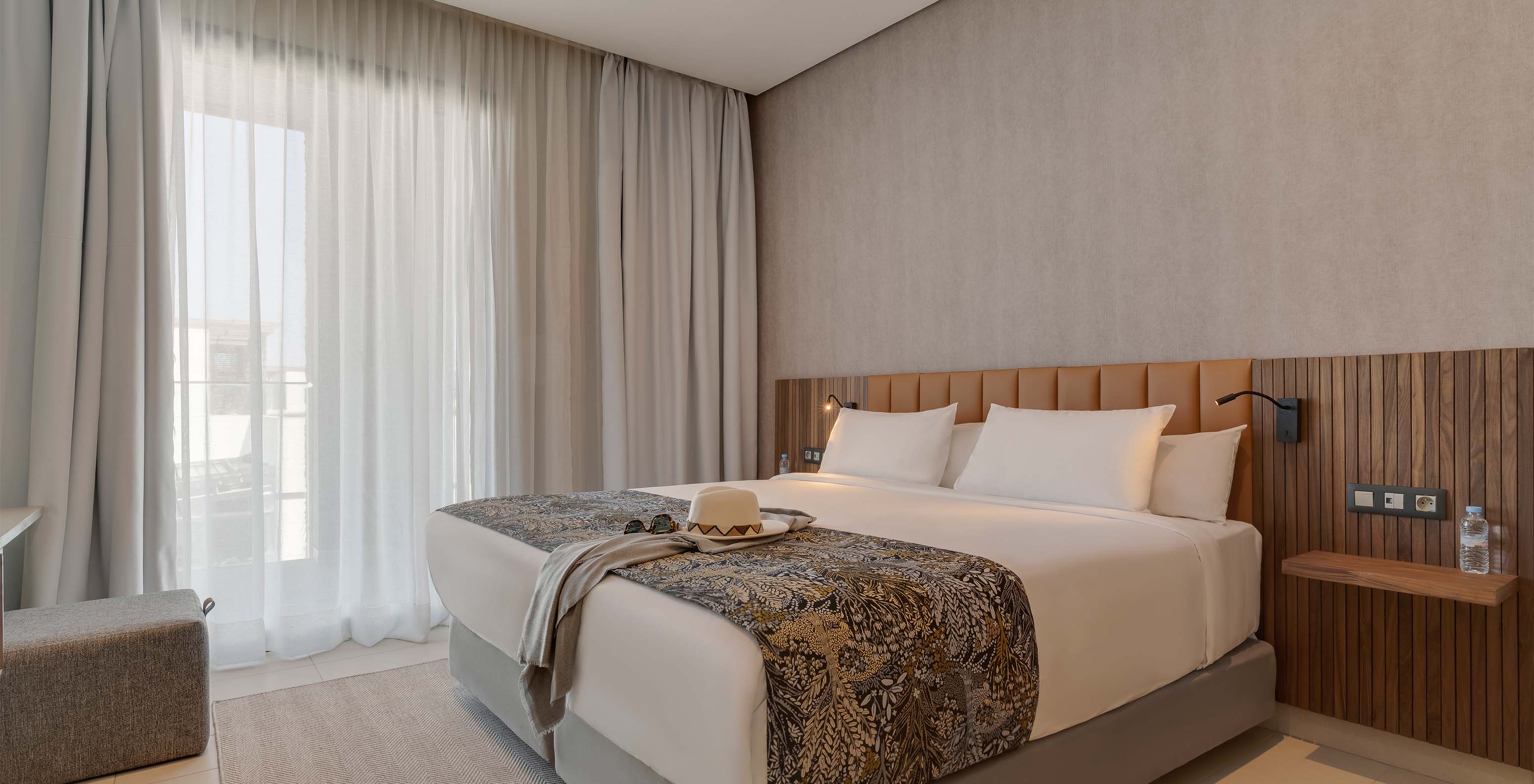A Suite Familiar Corniche do Pestana Casablanca tem um quarto com uma cama de casal com uma decoração moderna