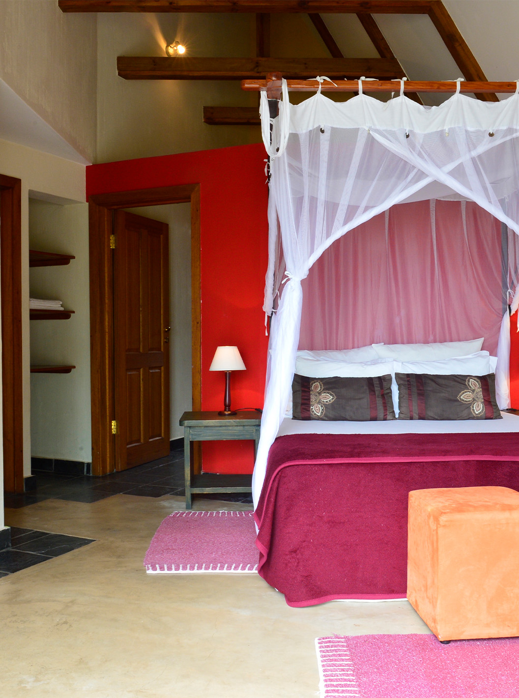 O Bungalow T1 do Pestana Bazaruto Lodge tem uma decoração em tons de vermelho com cama de casal, sofá e secretária