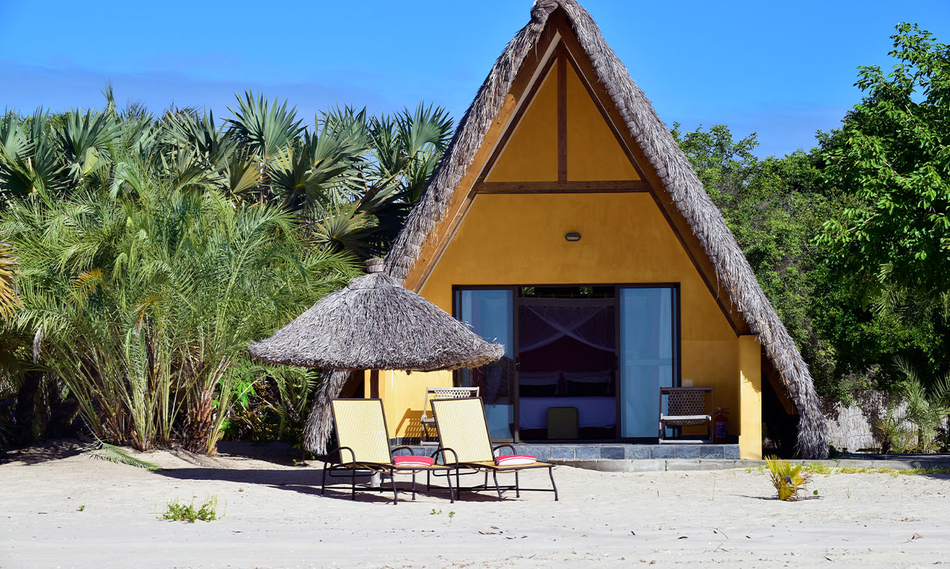 O Bungalow T1 do Pestana Bazaruto Lodge é uma casinha amarela na praia com telhado em palha e forma de A
