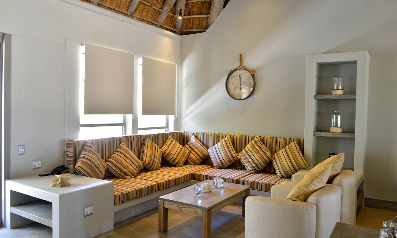 As Villas T2 do Pestana Bazaruto Lodge tem um sofá em L construído em pedra com almofadas coloridas e dois cadeirões