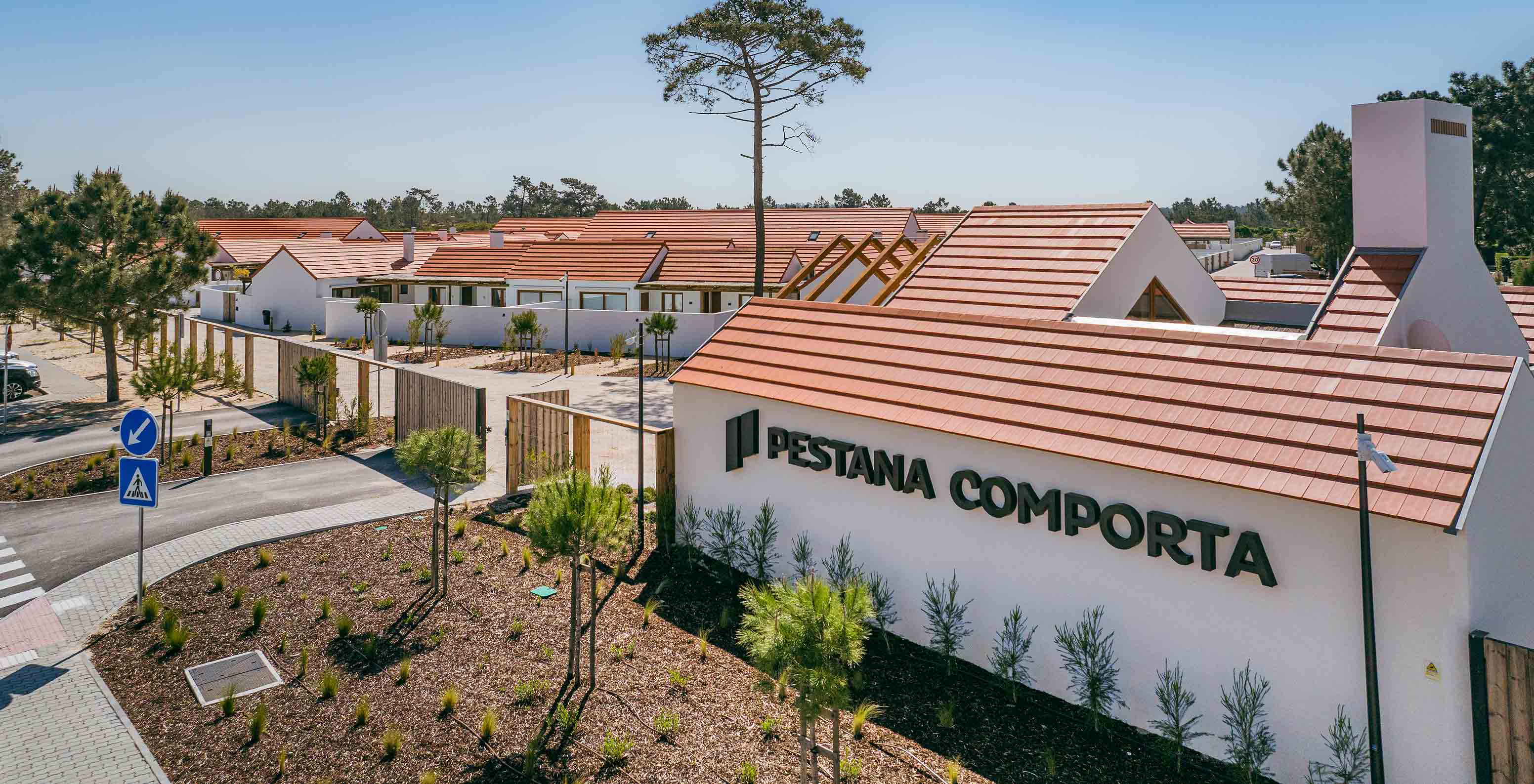 Vista do Pestana Comporta Village Residences, composto por villas de telhados vermelhos, rodeadas por vegetação e árvores