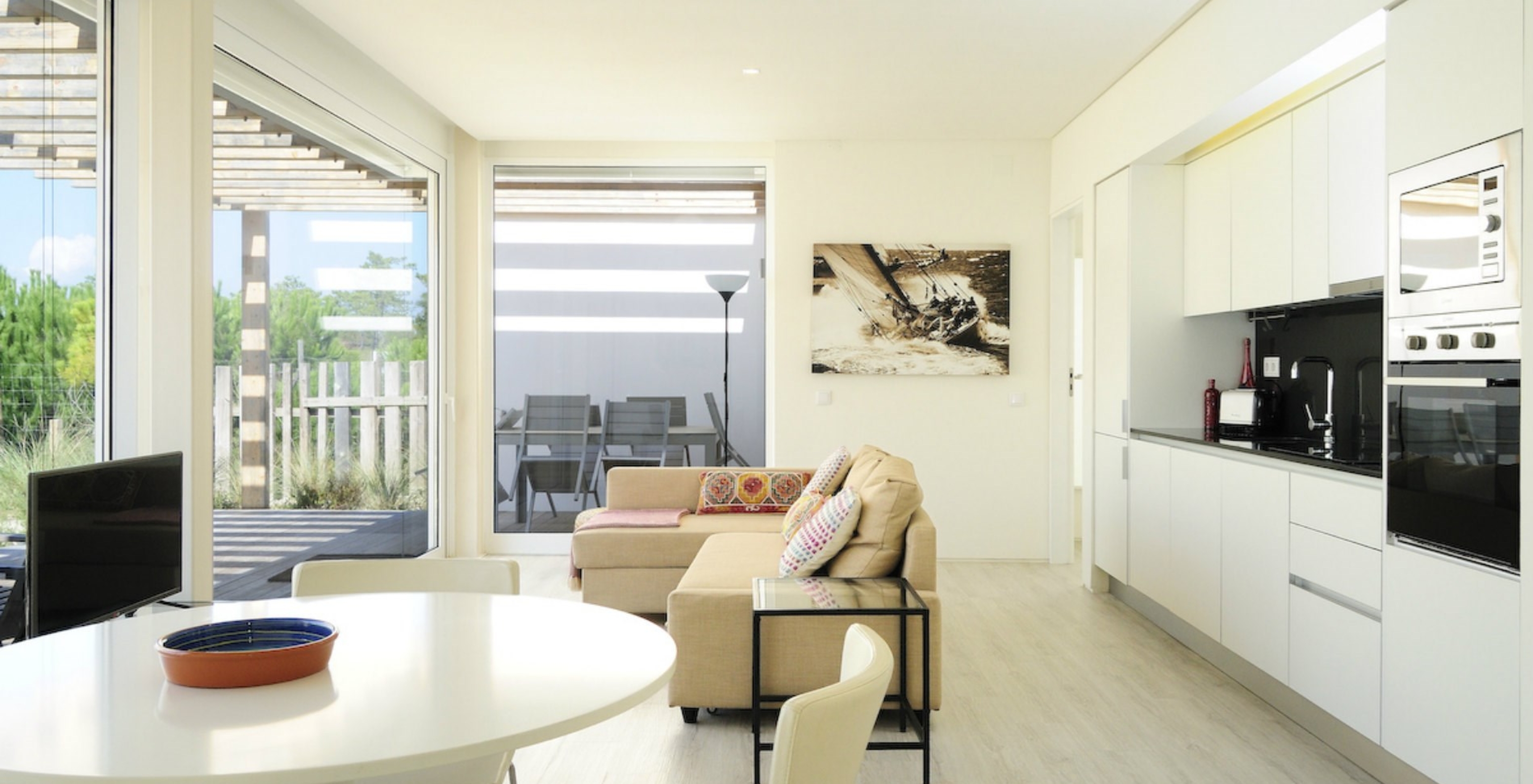 A Green Villa T3 do Pestana Tróia Eco Resort tem uma sala junta com a cozinha, sofá e mesa para jantar