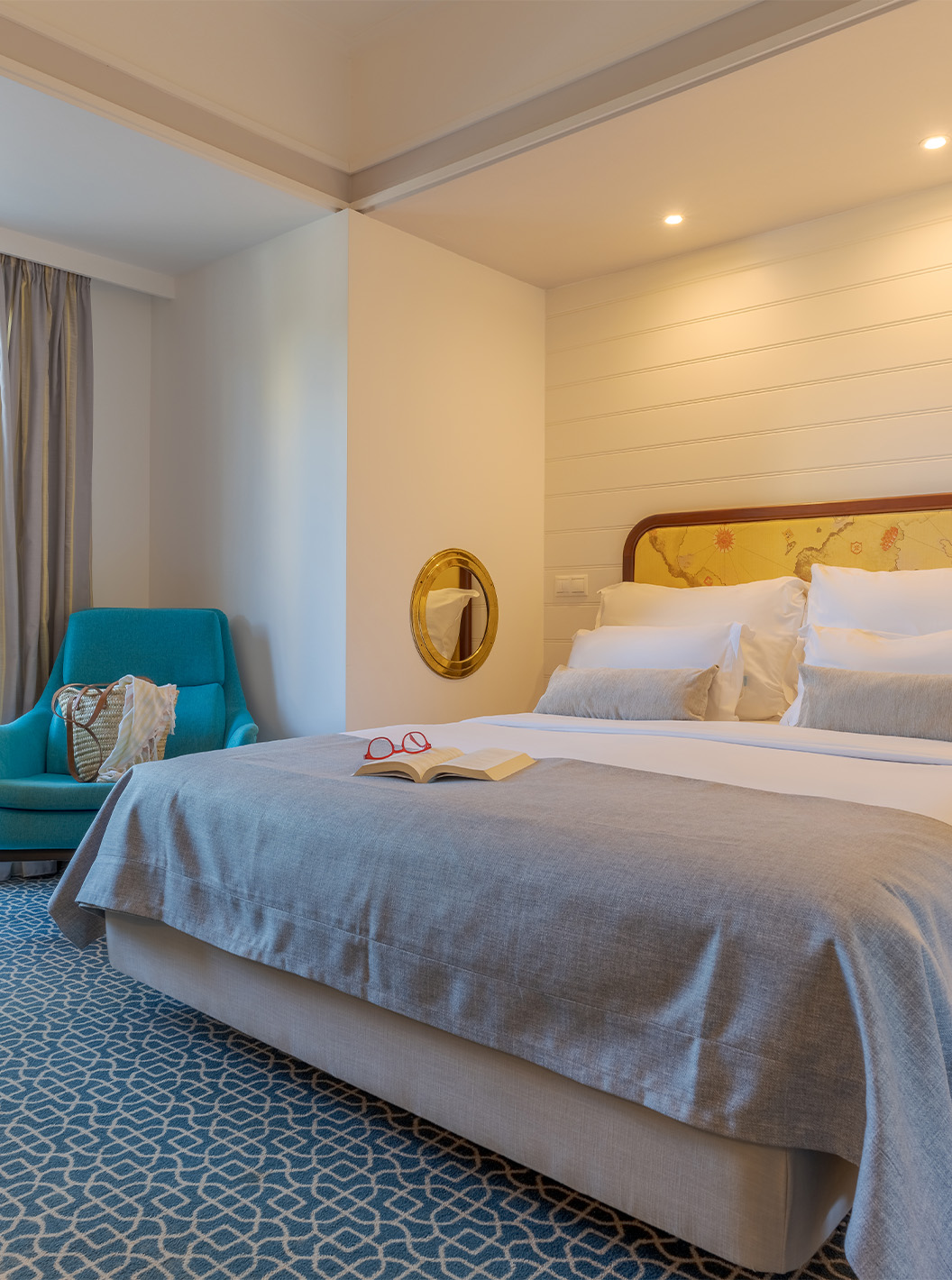 O Deluxe Vista Jardim do Pestana Alvor Praia tem uma cama de casal, cadeirão azul e janela para a varanda com cadeiras e mesa