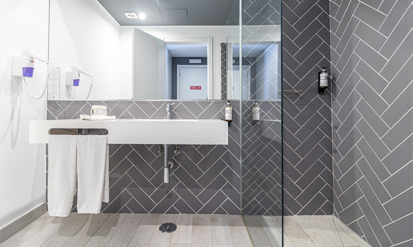 O Quarto Clássico do Pestana Gramacho Residences tem uma casa de banho moderna com lavatório branco, espelho e duche de vidro