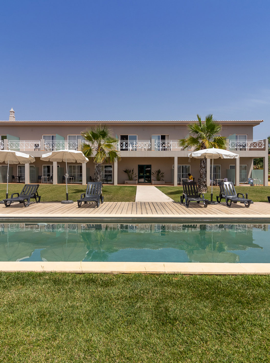 O Quarto Clássico do Pestana Gramacho Residences tem acesso à piscina, espreguiçadeiras e guarda-sóis em jardim cuidado