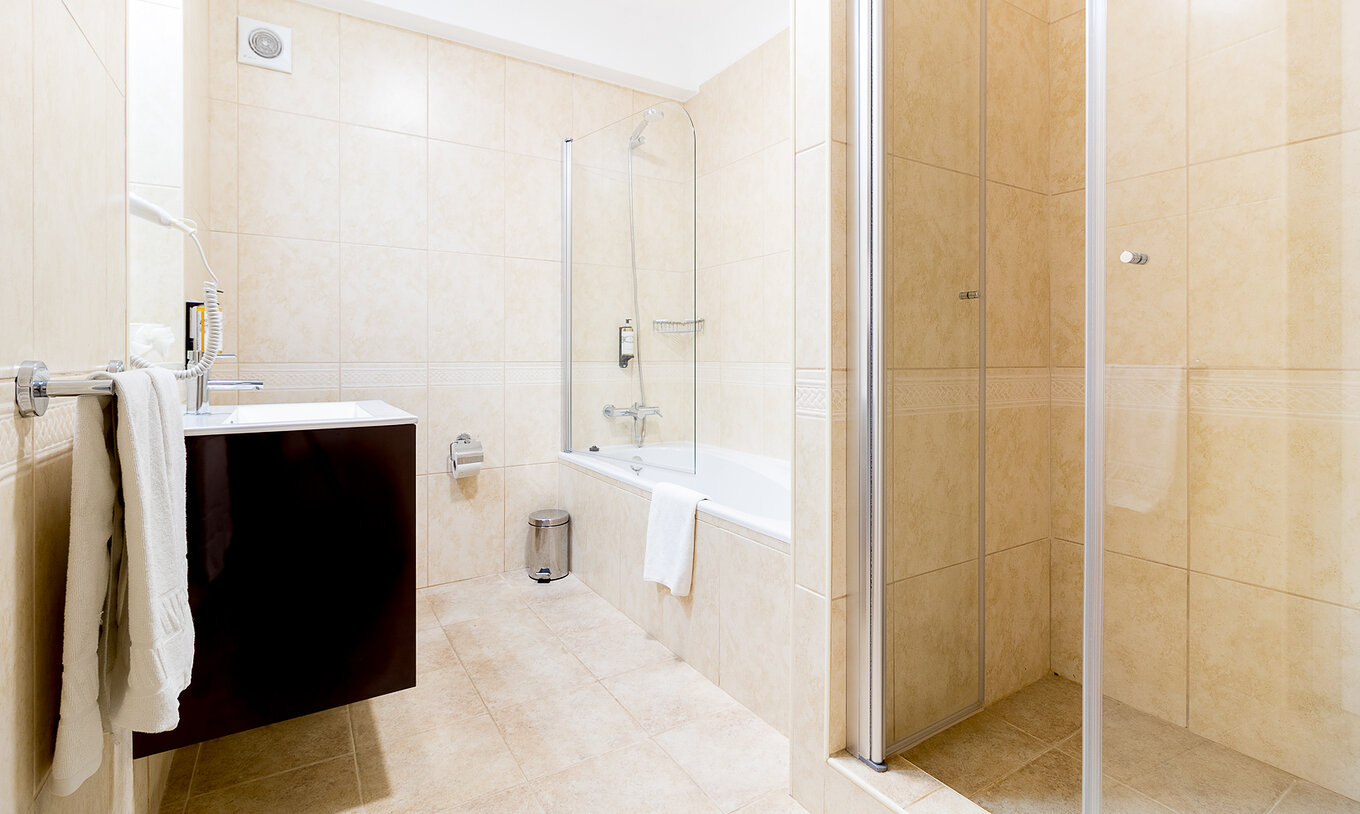 O Apartamento T2 do Pestana Gramacho Residences tem uma casa de banho clara com banheira, duche e um lavatório moderno