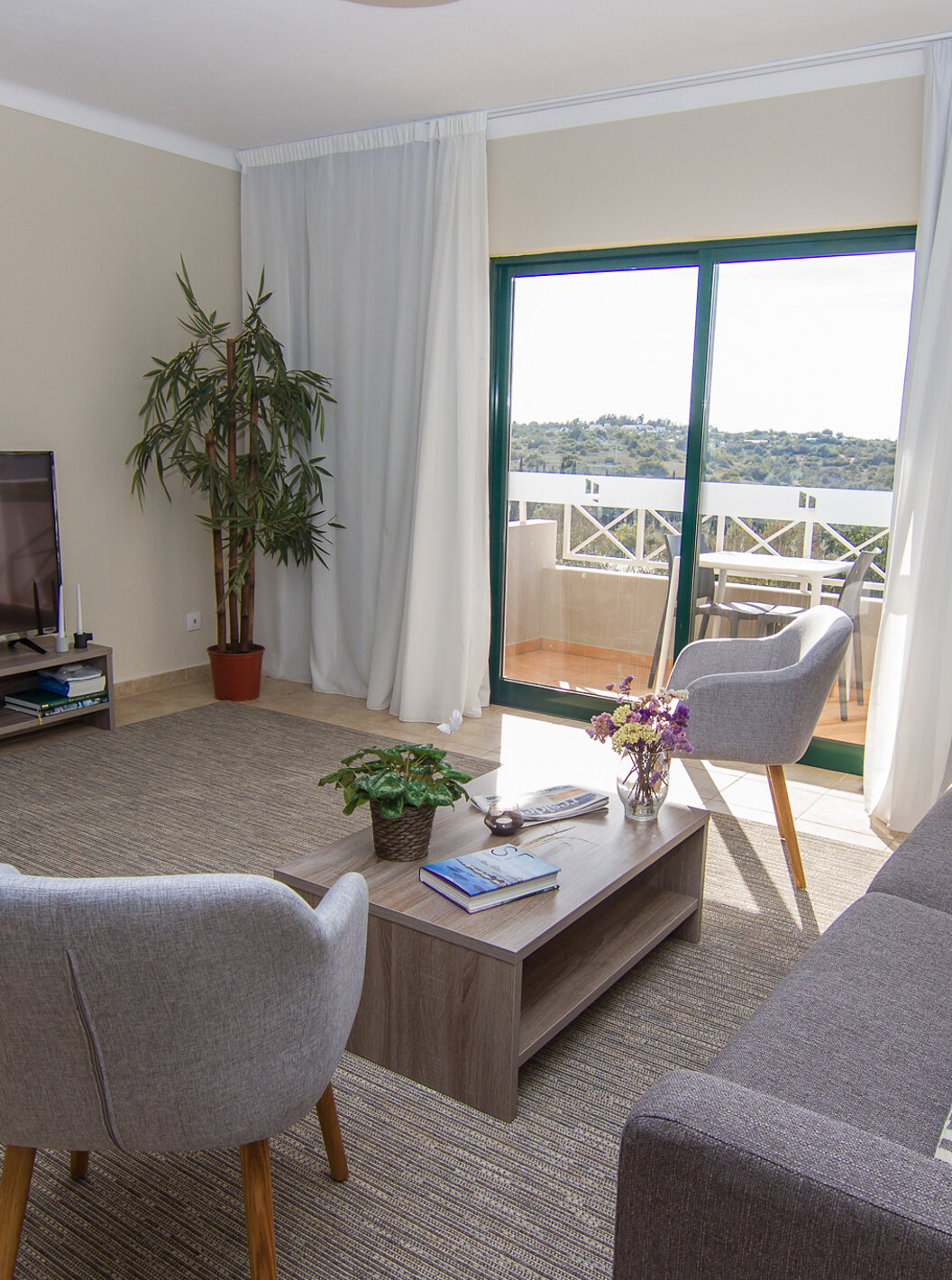 O Apartamento T2 do Pestana Gramacho Residences tem uma sala de estar com sofá, televisão e uma janela com uma varanda