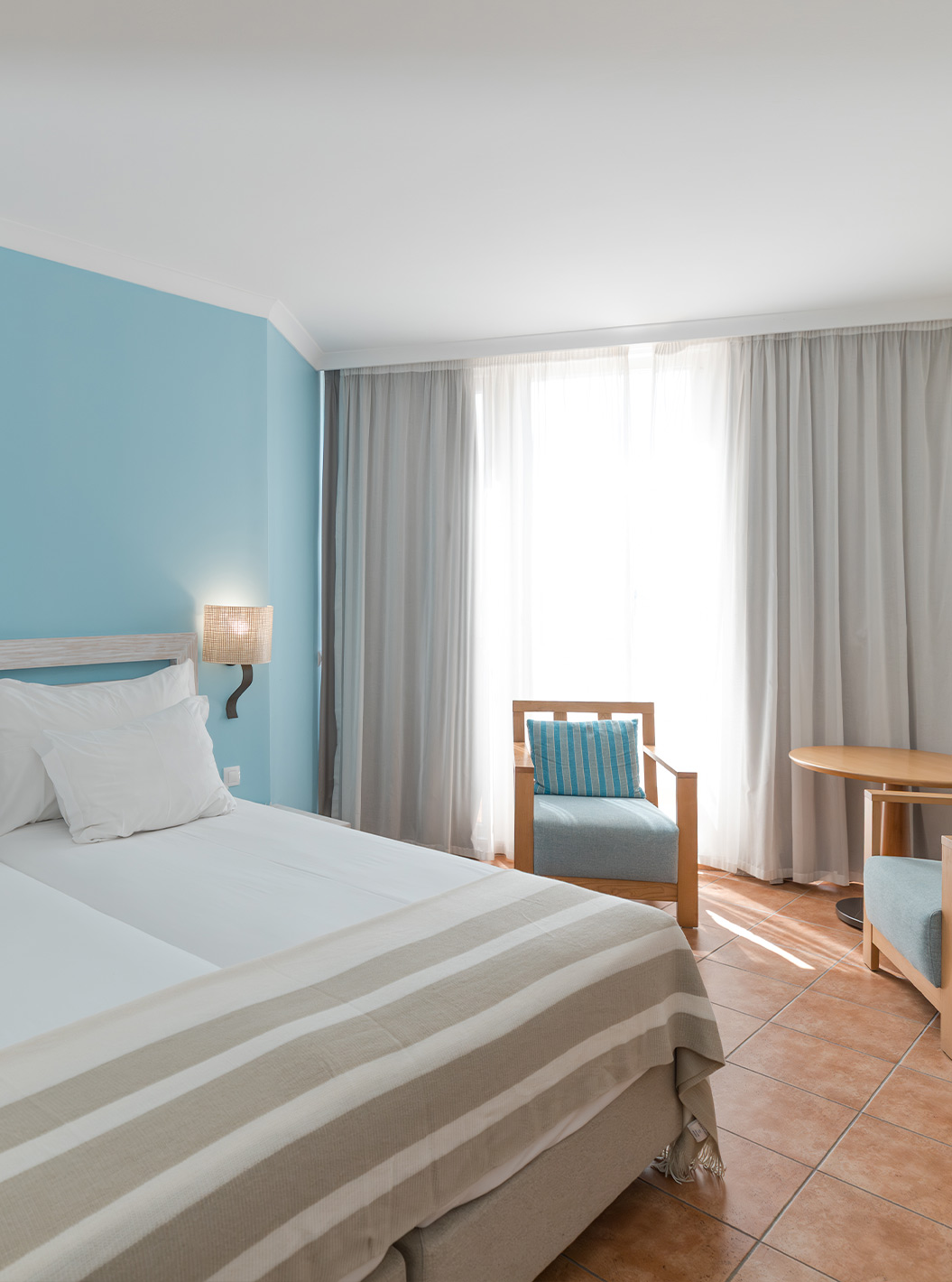 O Deluxe Vista Mar do Pestana Viking tem duas camas com mesa de cabeceira, duas poltronas e ar condicionado