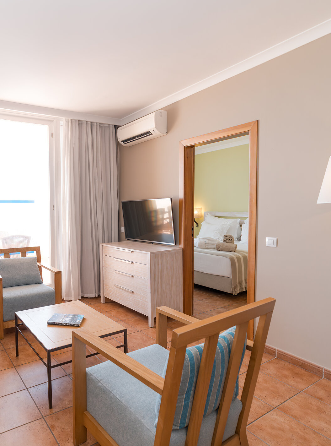 A Suite Vista Mar do Pestana Viking tem uma sala com sofá, poltronas, televisão, ar condicionado e acesso à varanda
