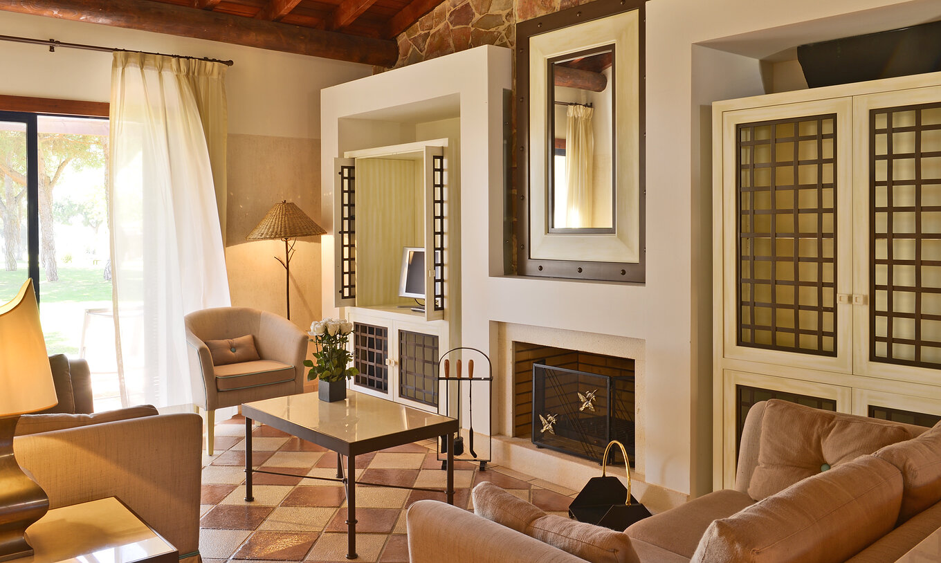 A Suite Vista Jardim Vila Sol do Pestana Vila Sol - Vilamoura tem uma sala com sofás, mesa de centro, lareira e janela
