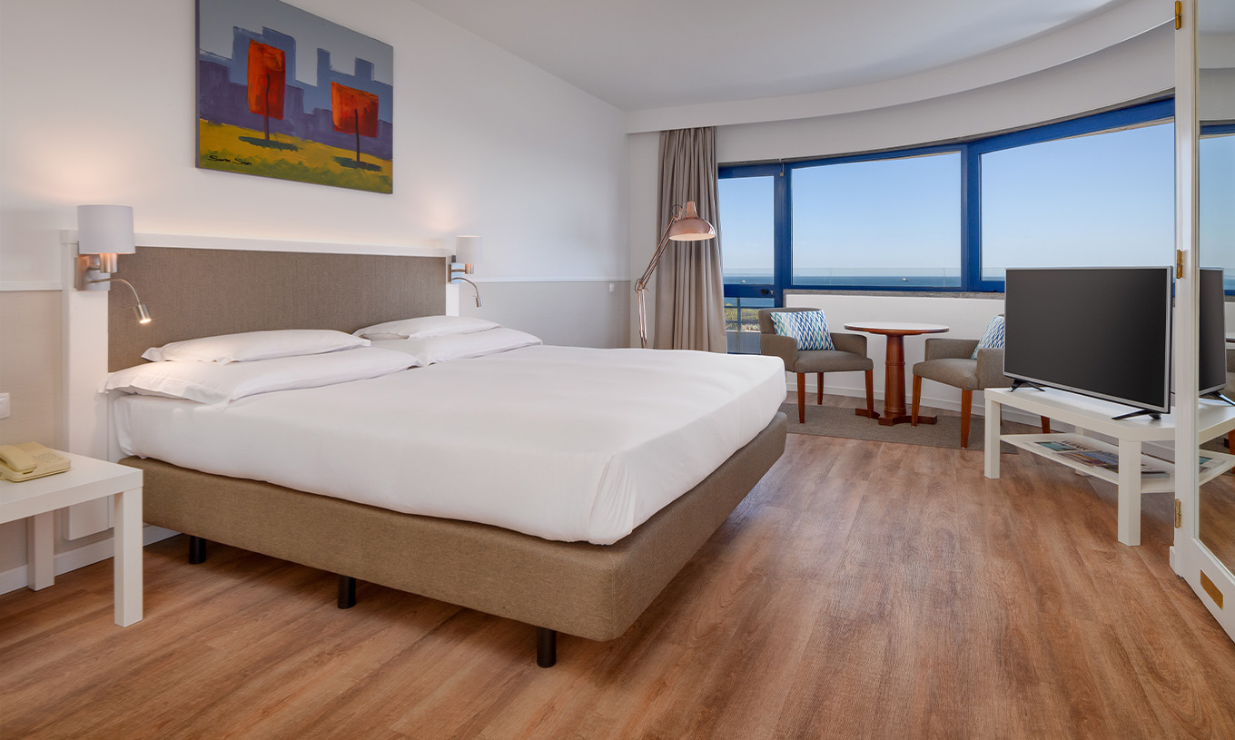 A Suite Deluxe Vista Mar do Pestana Cascais conta com cama de casal, televisão, e um quadro pintado na parede