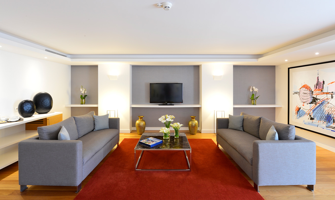 A Suite Presidencial do Pestana Cidadela Cascais tem uma sala com dois sofás grandes, uma mesa de centro e uma televisão