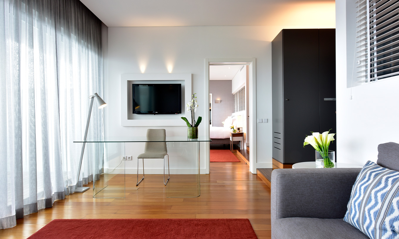 A Suite Vista Mar do Pestana Cidadela Cascais tem uma sala de estar com sofá, televisão, secretária e mesa