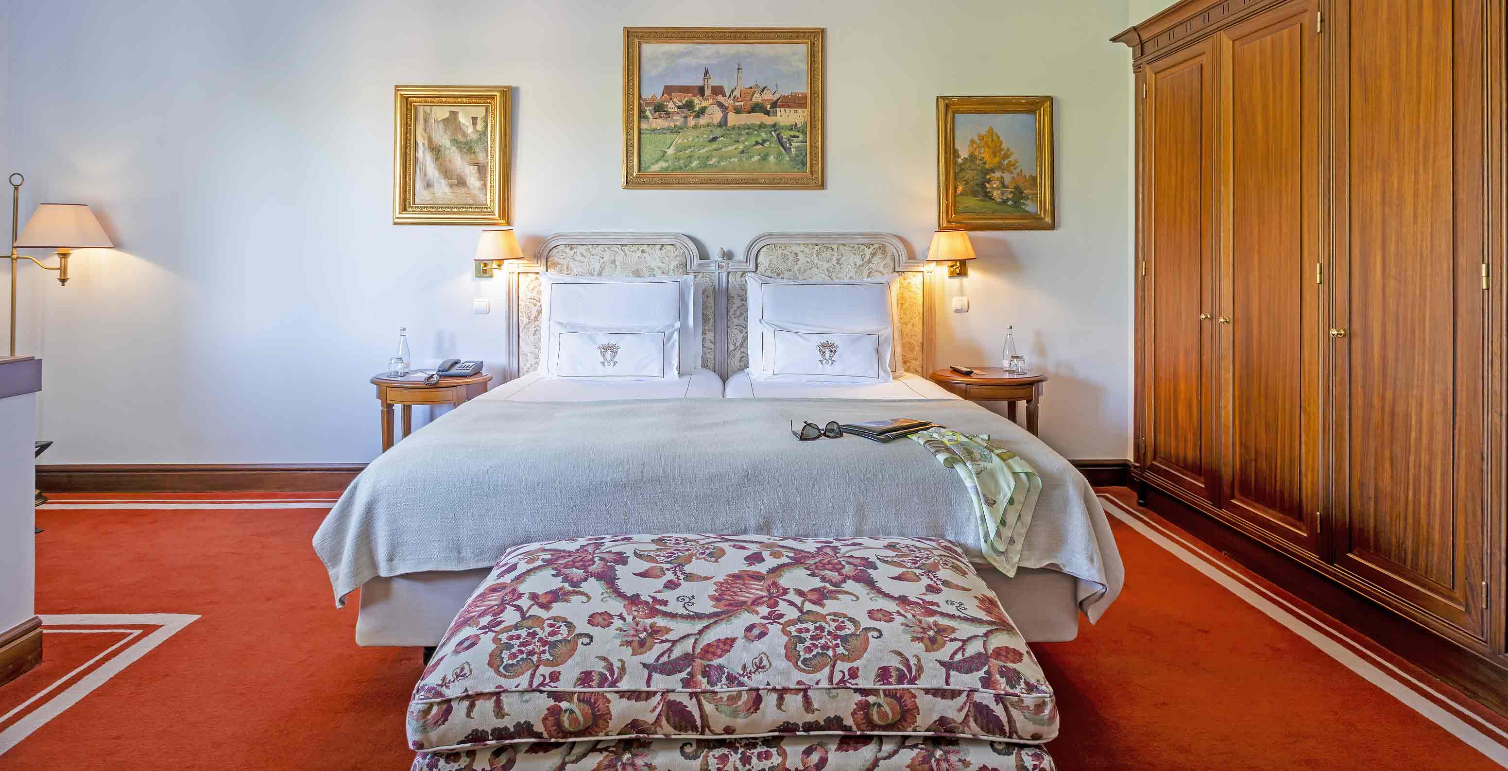 A Suite do Pestana Palace Lisboa tem uma cama de casal com uma banqueta nos pés da cama e um armário grande