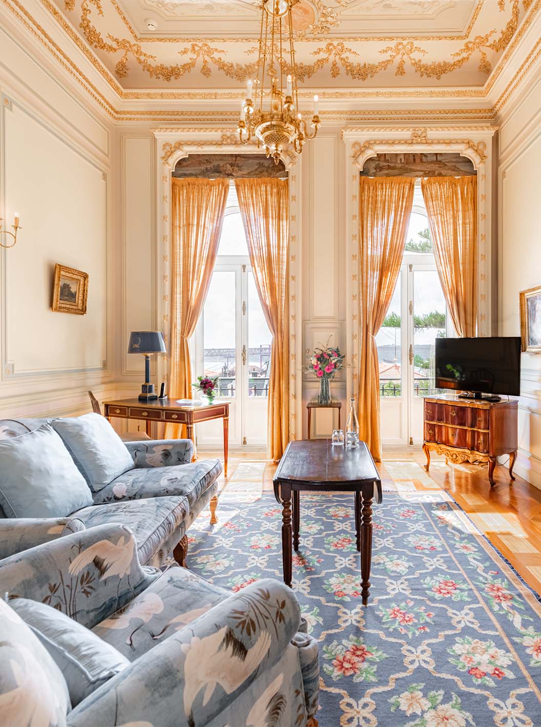 A Suite D. Manuel/ D. Luís Filipe do Pestana Palace Lisboa tem uma sala de estar luxuosa com sofá, televisão, janela e tapete