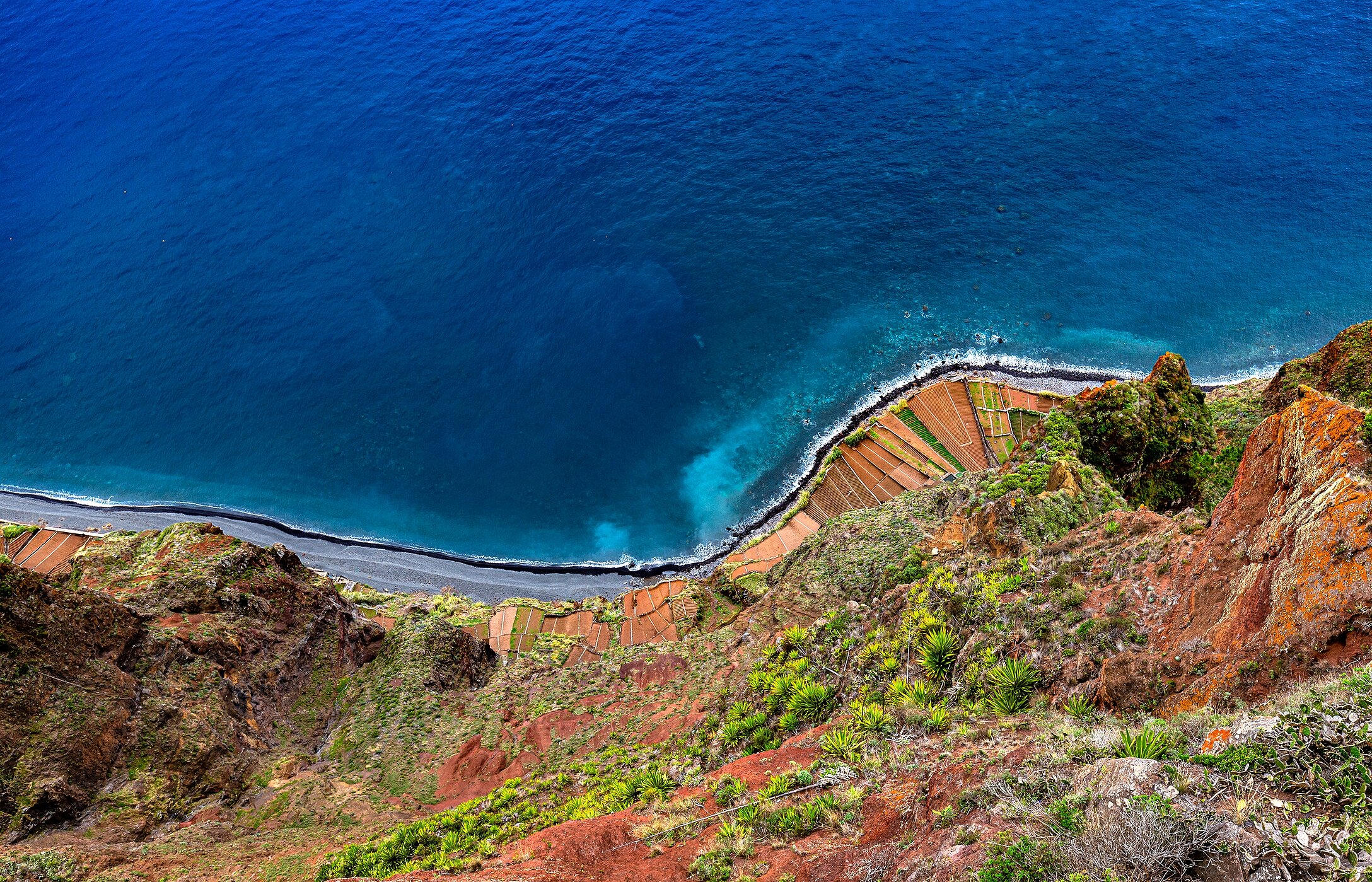 Vista a partir do miradouro do Cabo Girão onde se vê a linha do mar azul e a falésia