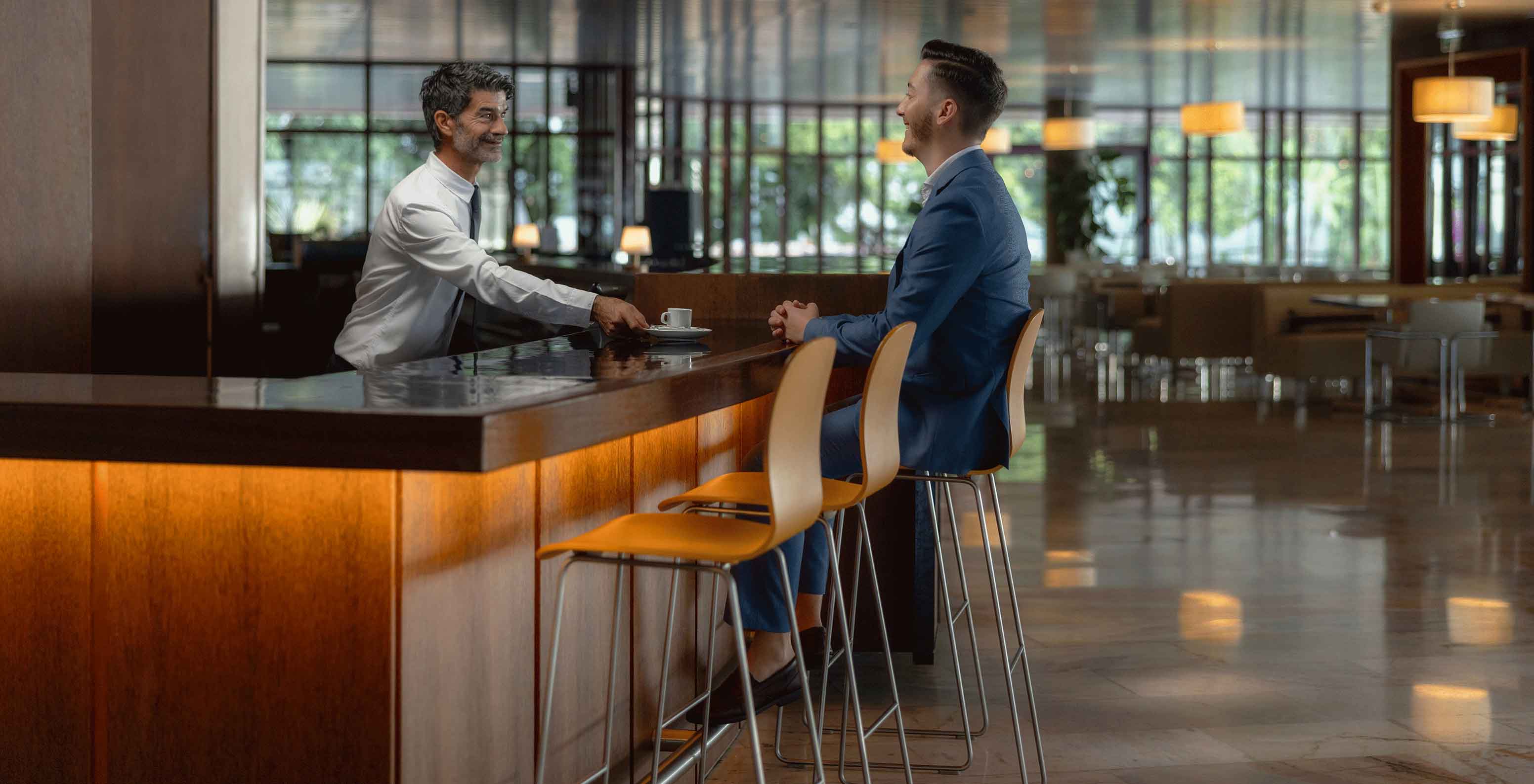 Zona do bar do hotel no Funchal em Frente ao Mar, com Spa e Piscina, com um senhor a servir bebidas ao balcão