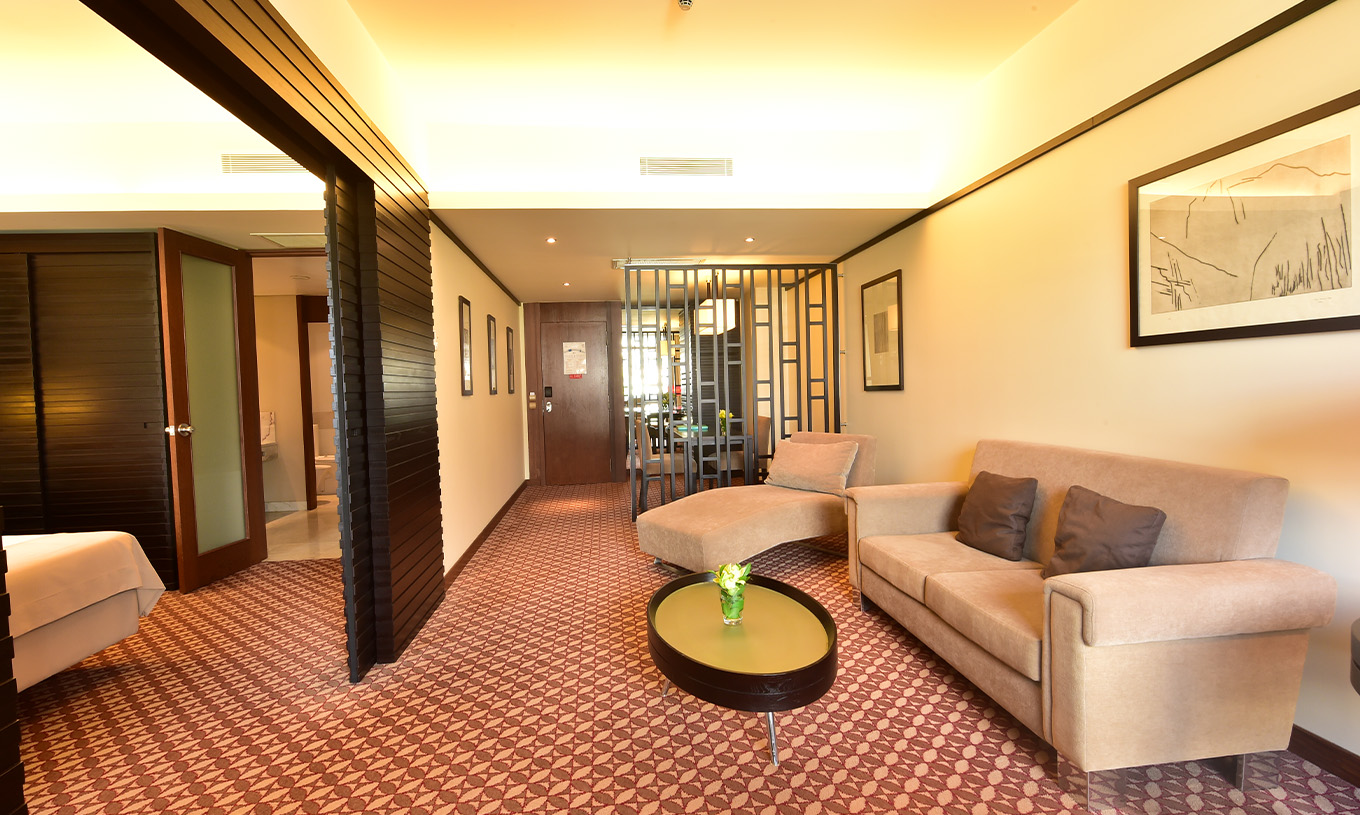 O Clássico Vista Terra do Pestana Casino Park tem uma zona de estar, com um sofá, uma chaise longue e uma mesa de apoio