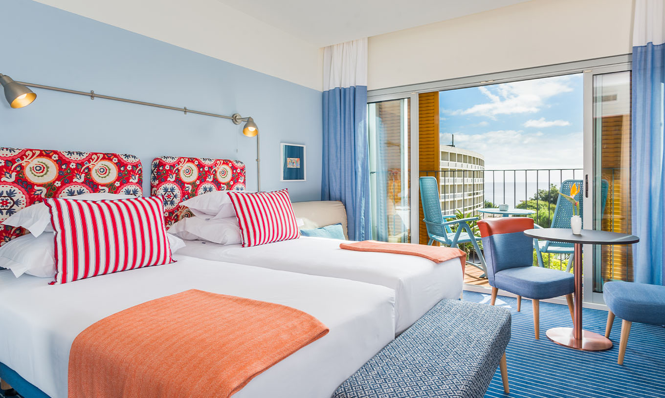 O Estúdio Deluxe Vista Mar do Pestana Casino Studios tem duas camas de casal com cabeceira com padrão, varanda e mesa