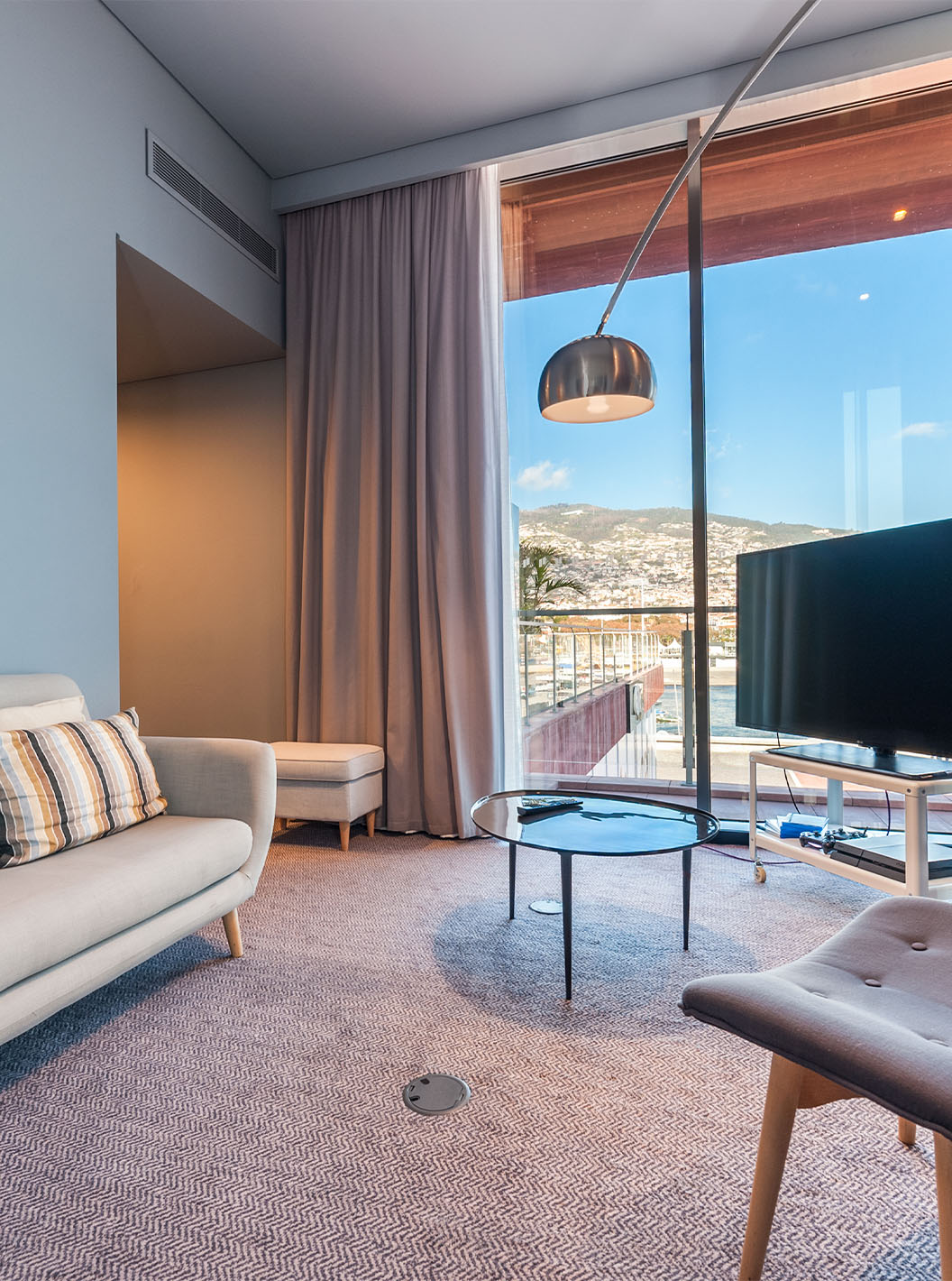 A CR7 Suite do Pestana CR7 Funchal tem uma sala de estar com um sofá, uma televisão e uma janela com vista para o Funchal