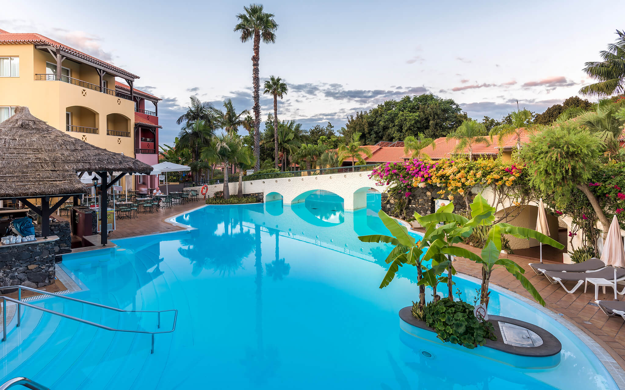 Piscina ao ar livre cercada por plantas tropicais e árvores do Pestana Village um Hotel Romântico no Funchal, na Madeira
