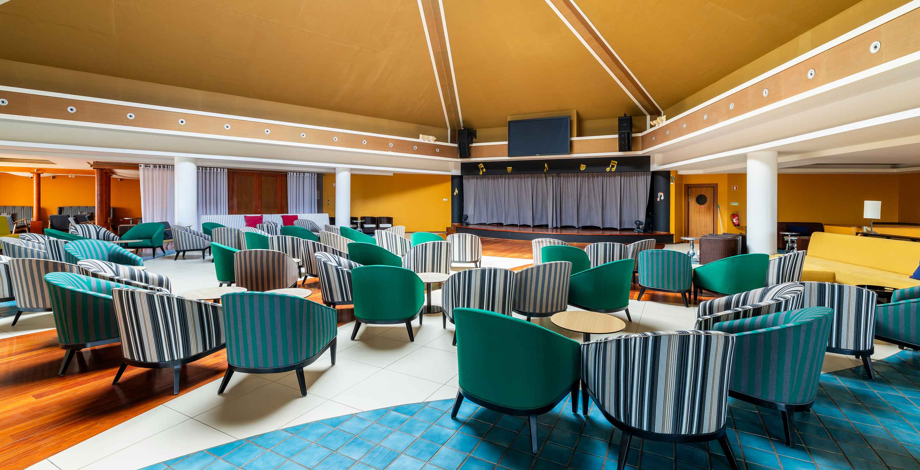 O bar Sunset, do Resort de 5 Estrelas no Porto Santo tem um espaço amplo com paredes amarelas e cadeiras verdes