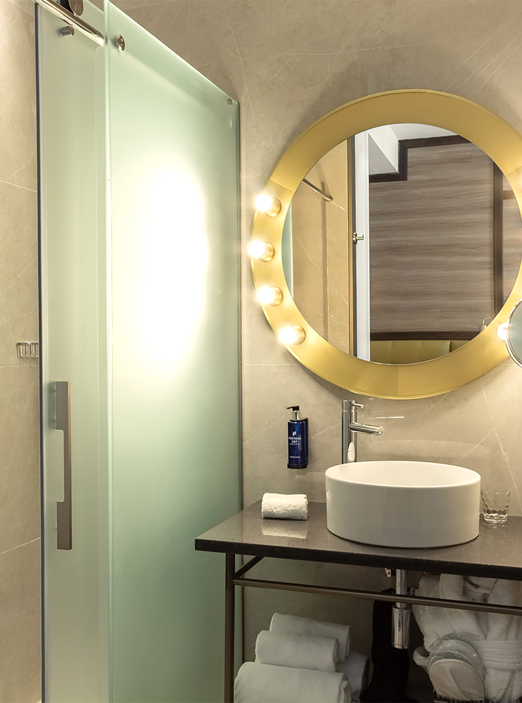 O Premium do Pestana CR7 Gran Vía Madrid tem uma casa de banho com um espelho e luzes, lavatório e portas de vidro de correr