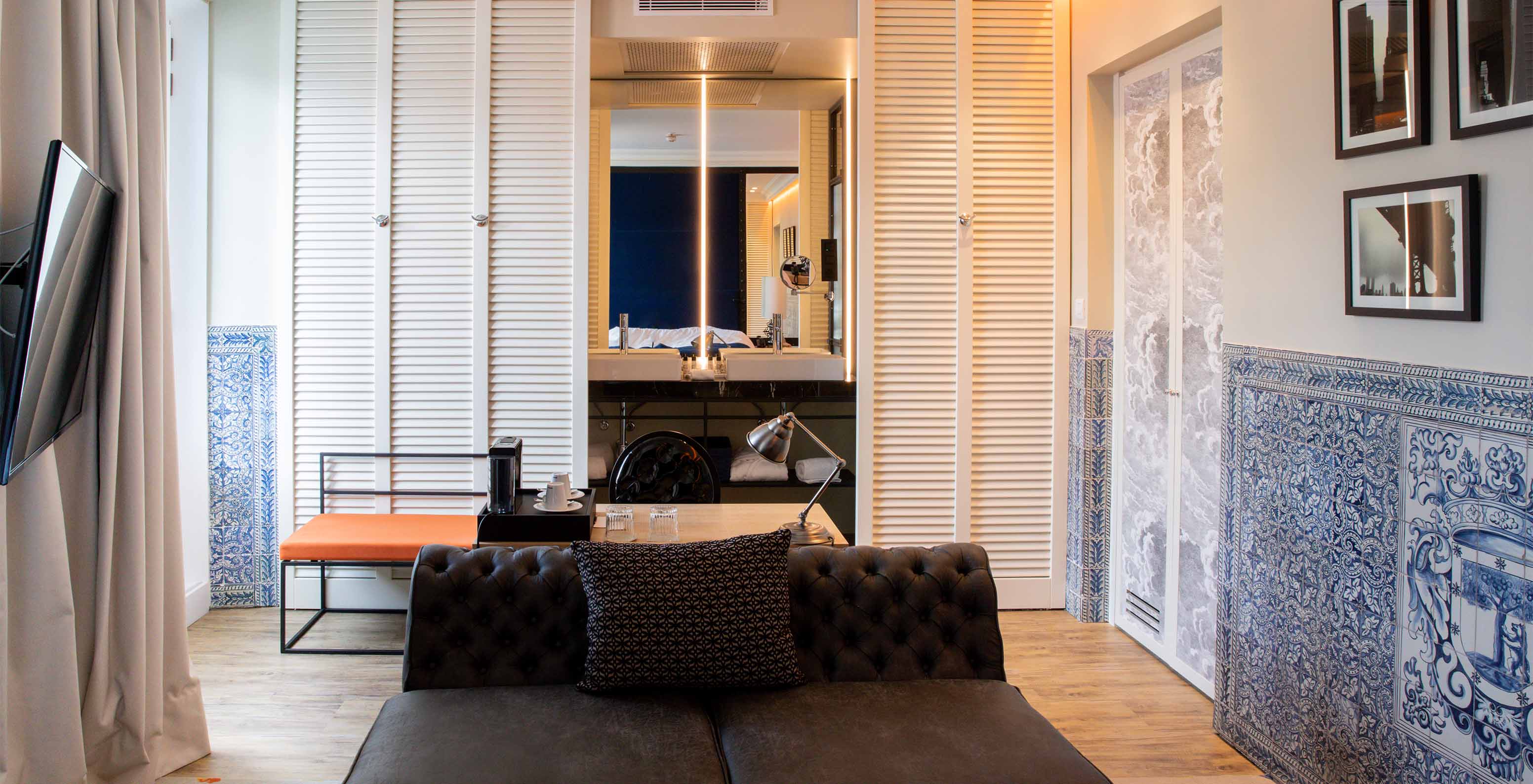 O Deluxe Plaza Mayor do Pestana Collection Plaza Mayor tem uma sala com sofá, televisão e azulejos azuis e brancos na parede