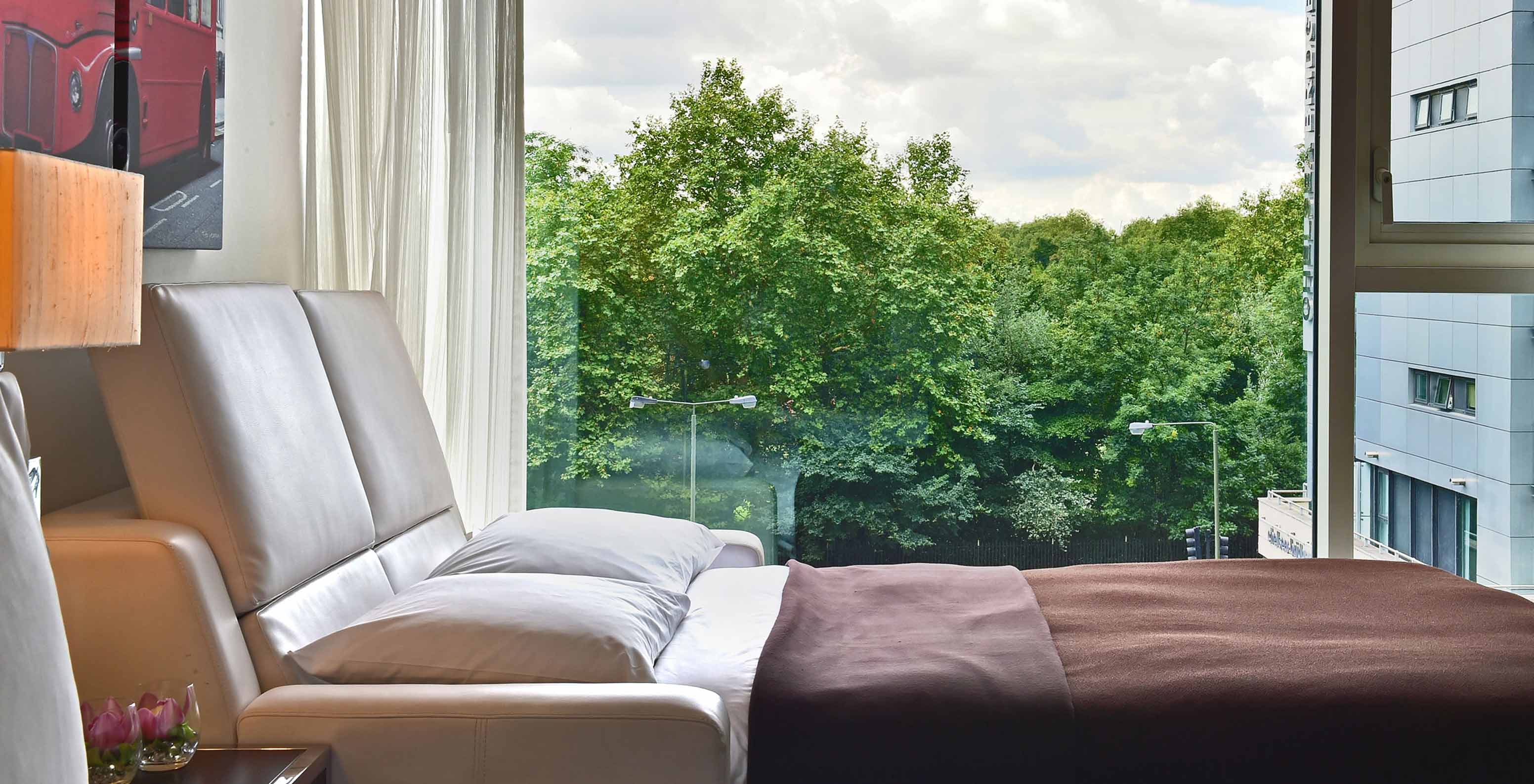 O Deluxe Family do Pestana Chelsea Bridge tem sofá cama aberto, quadros de londres e janela grande com vista e cortinas