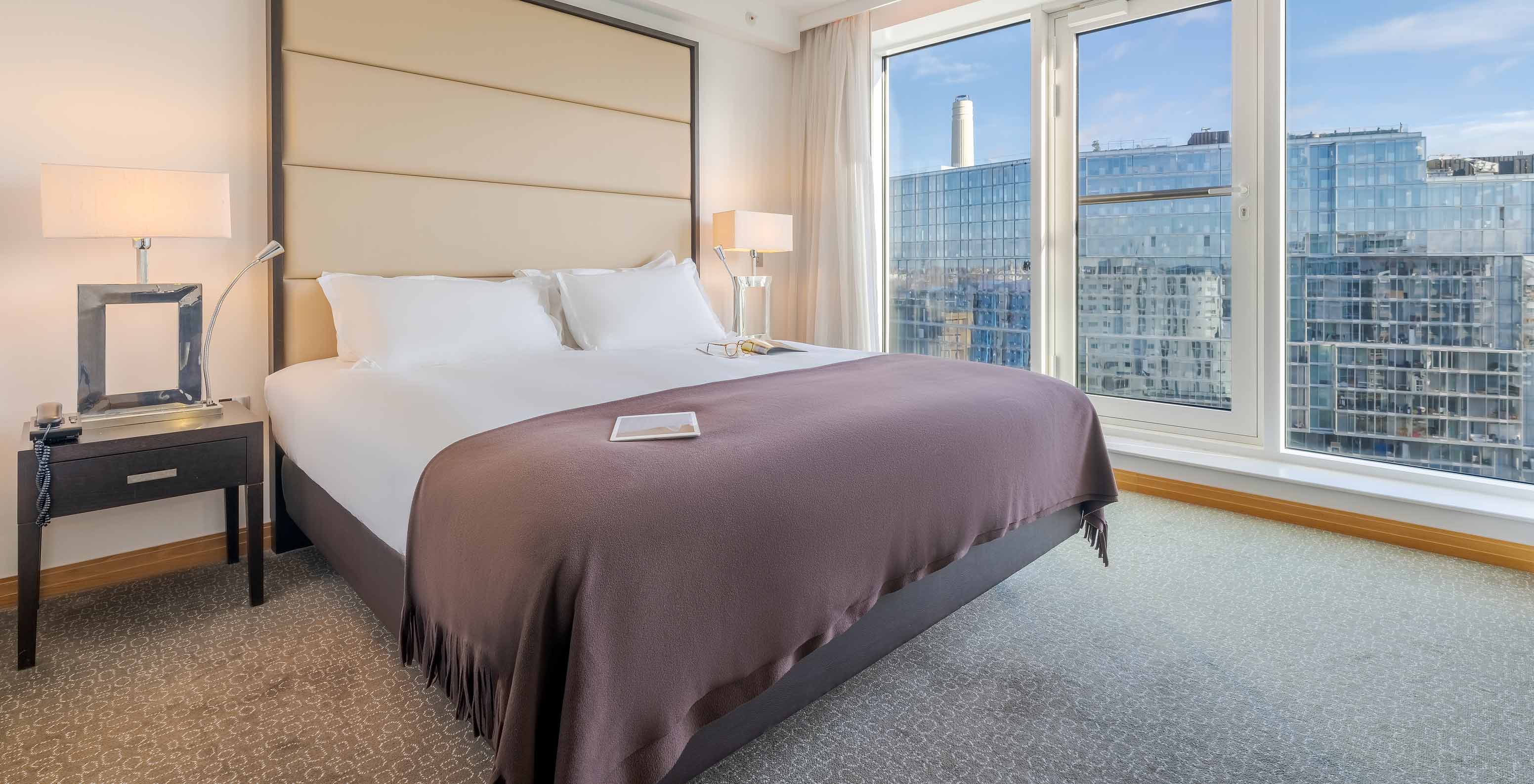 O Superior King do Pestana Chelsea Bridge tem cama de casal com lençóis brancos e janela grande com vista para a cidade