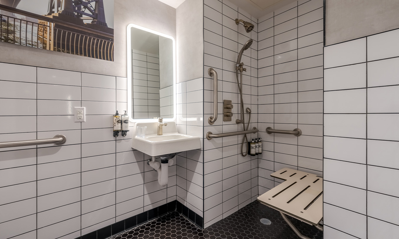 O Comfort Room ADA do Pestana CR7 Times Square tem uma casa de banho adaptada com duche, lavatório, e espelho