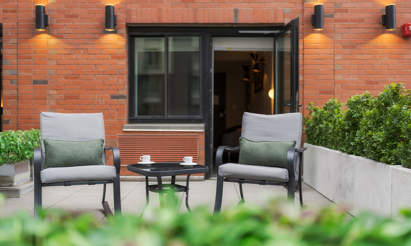 A Junior Suite ADA with Balcony and View do Pestana CR7 Times Square tem uma varanda com duas cadeiras e uma mesa