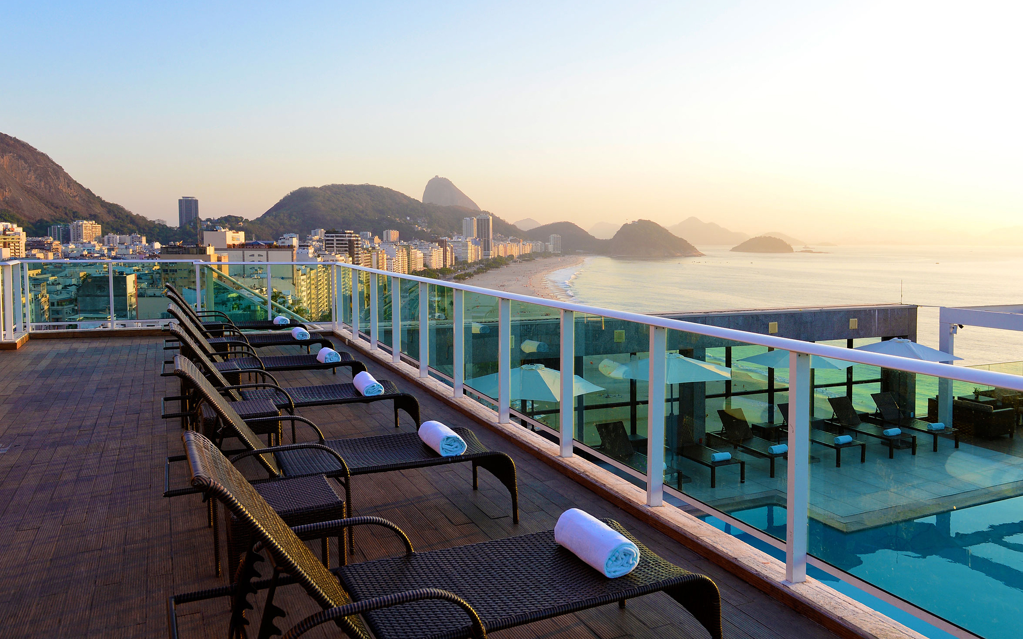 Rooftop do hotel 4 estrelas no Rio de Janeiro, com espreguiçadeiras com toalhas e vista para a Praia de Copacabana