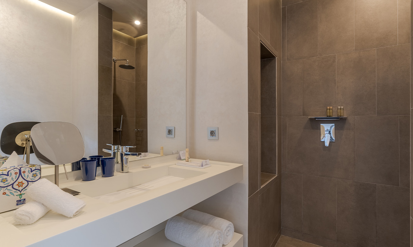 A CR7 Suite do Pestana CR7 Marrakech tem uma casa de banho com walk-in shower e lavatório com um espelho grande