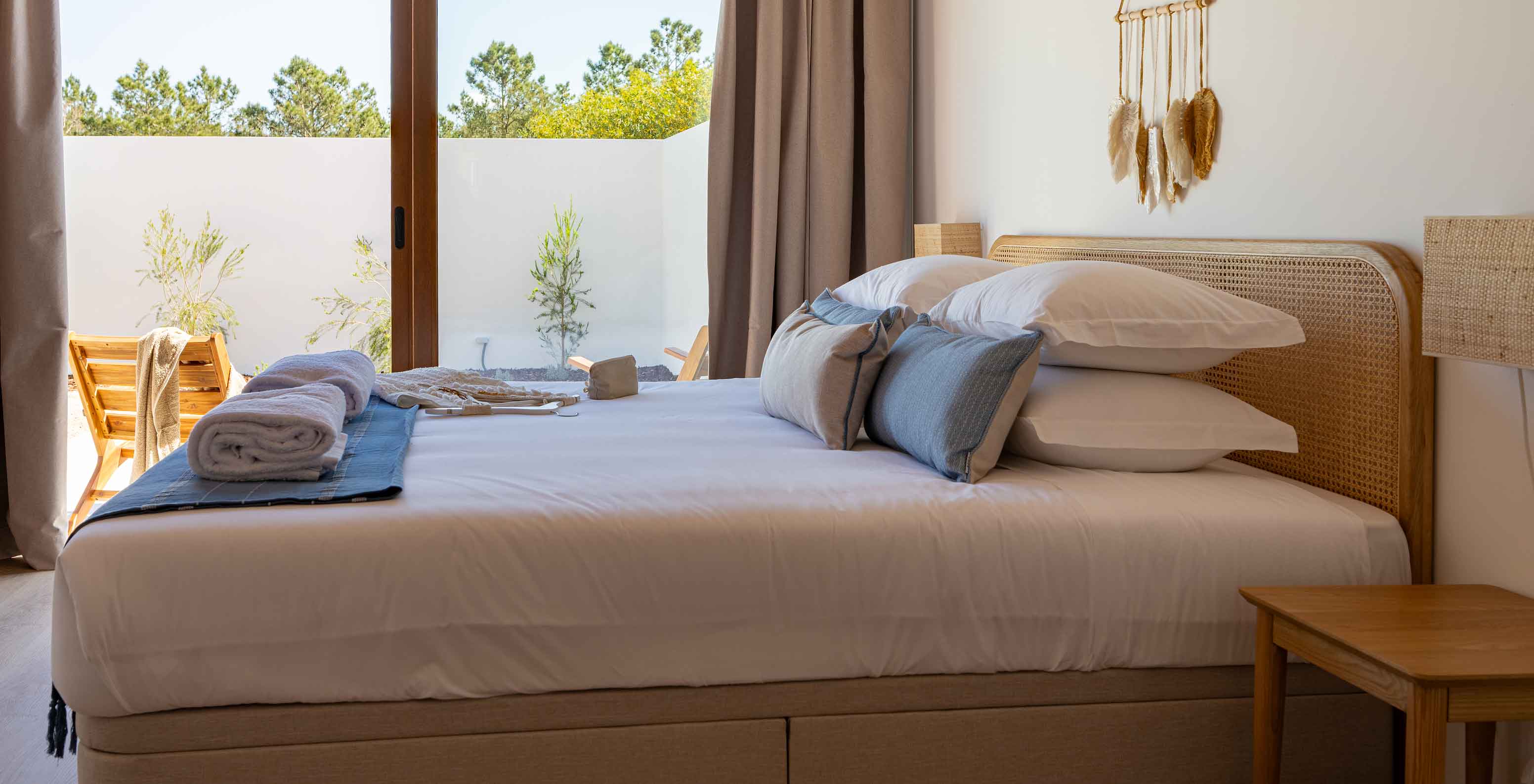 A Premium Green Villa do Pestana Comporta Village Residences tem um quarto com uma cama de casal e uma grande janela 
