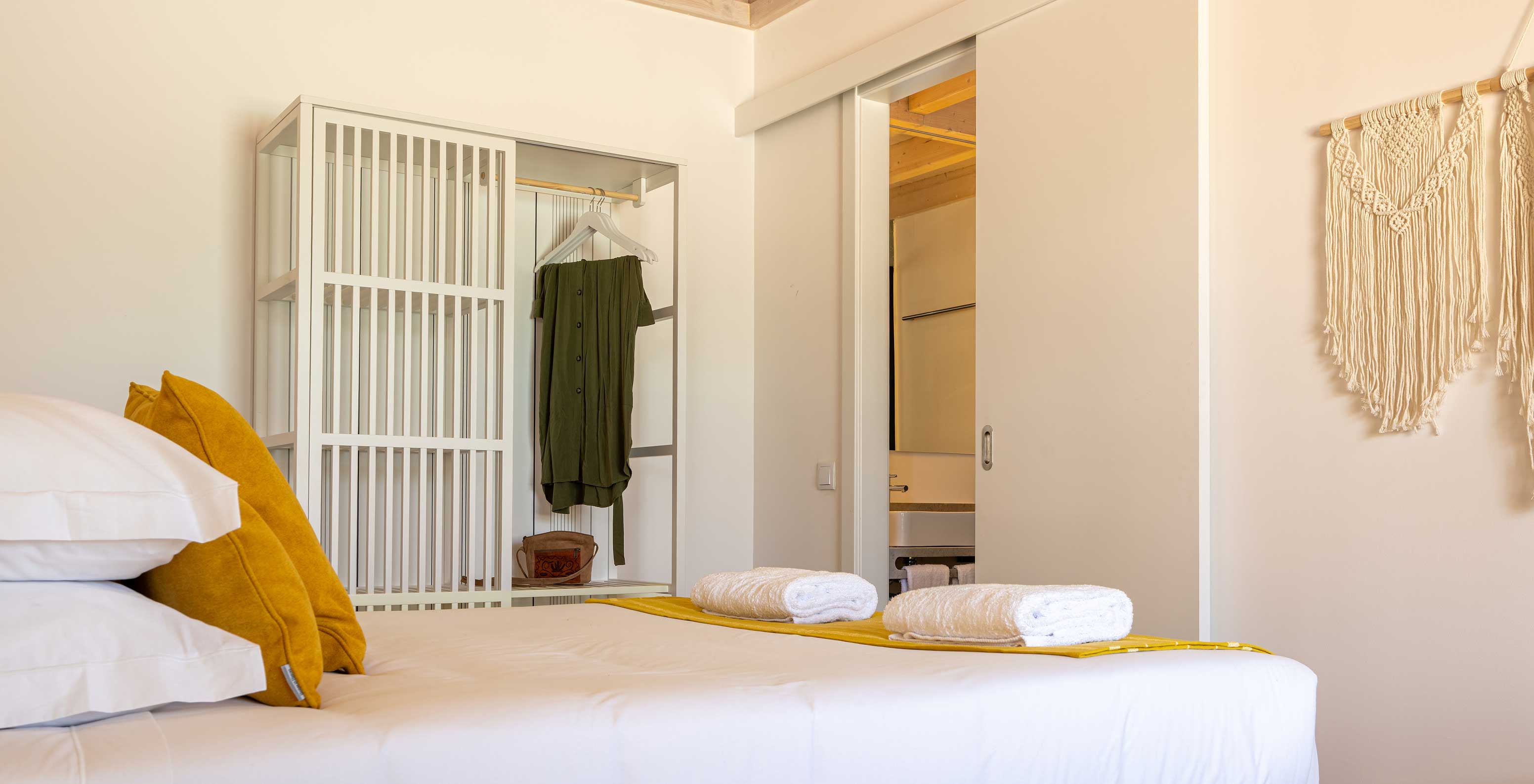 A Premium Villa do Pestana Comporta Village Residences tem um quarto minimalista com uma cama e um banco