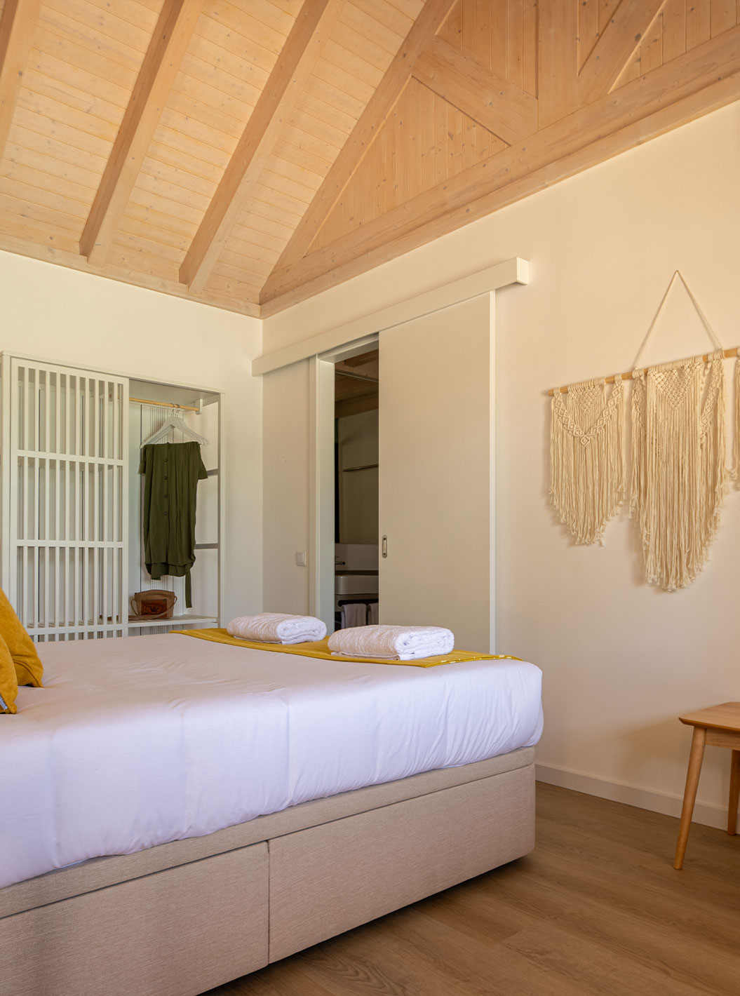 A Standard Green Villa do Pestana Comporta Village Residences tem um quarto minimalista com uma cama e um banco
