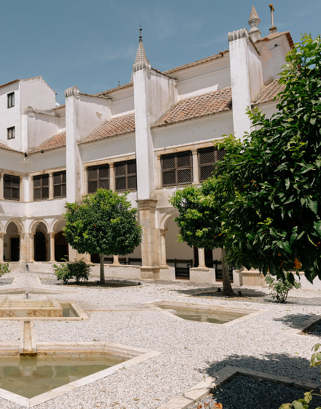 Pátio interior da Pousada Convento Vila Viçosa, no centro histórico, com várias laranjeiras e uma fonte no centro