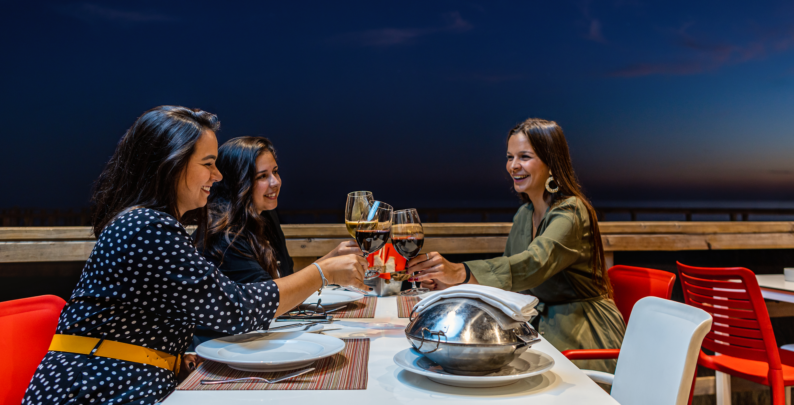 Amigas a brindar e desfrutar de um delicioso jantar e de um copo de vinho na esplanada do restaurante Sea Deck