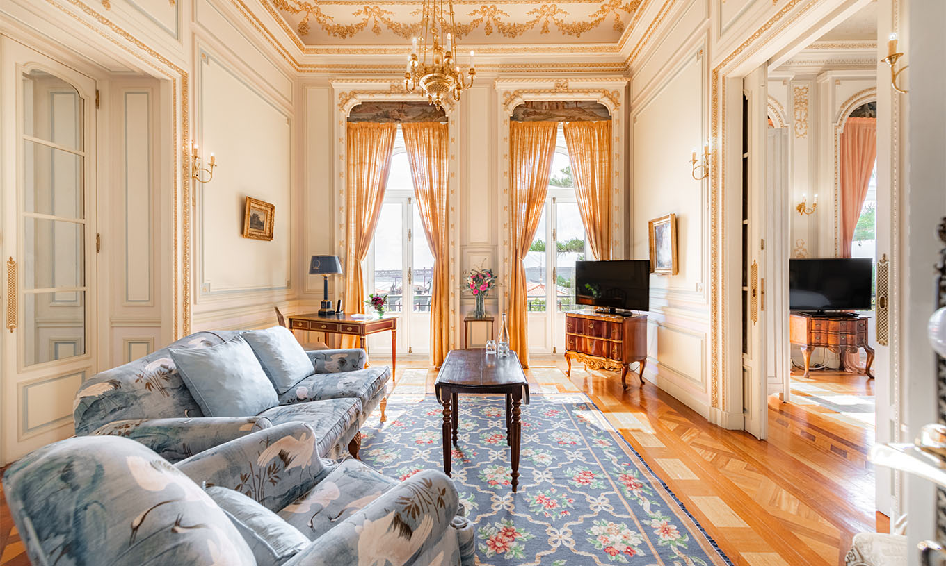 A Suite D. Manuel/ D. Luís Filipe do Pestana Palace Lisboa tem uma sala de estar luxuosa com sofá, televisão, janela e tapete