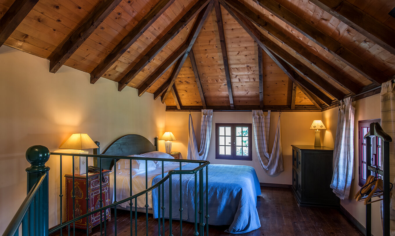 As Villas Duplex do Pestana Quinta do Arco têm cama de casal com teto de madeira, mesas de cabeceira e cómoda em madeira
